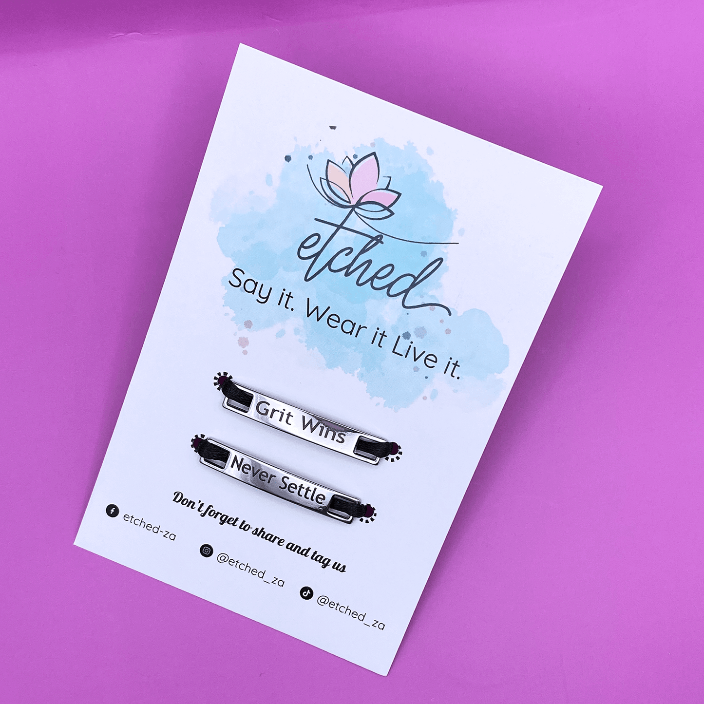 Image of etched product card showing the Grit Wins Never Settle shoe tags on a purple background