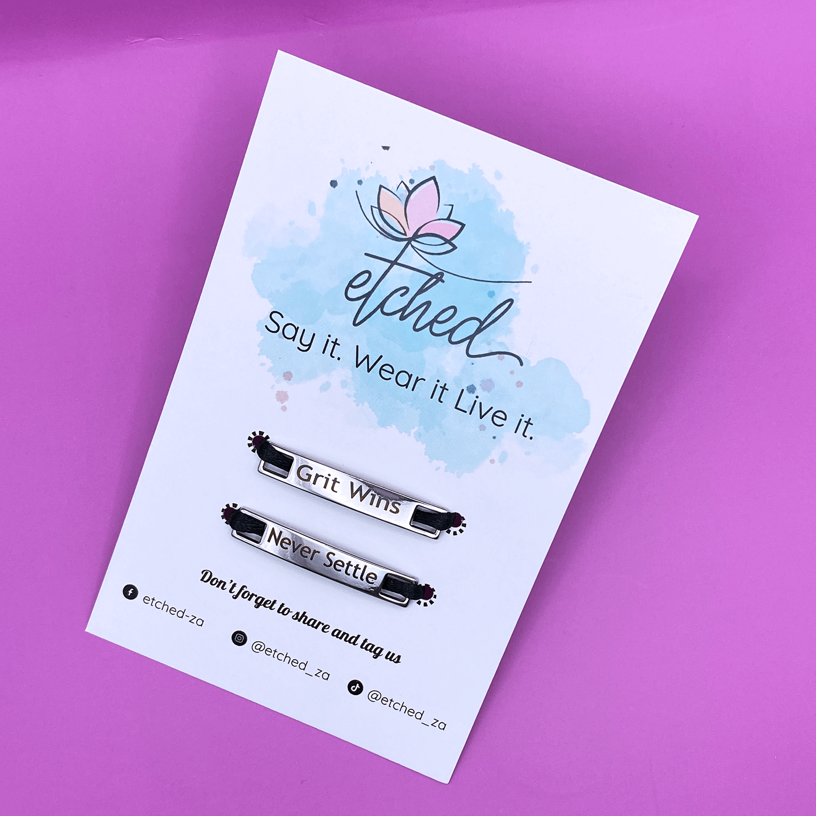 Image of etched product card showing the Grit Wins Never Settle shoe tags on a purple background