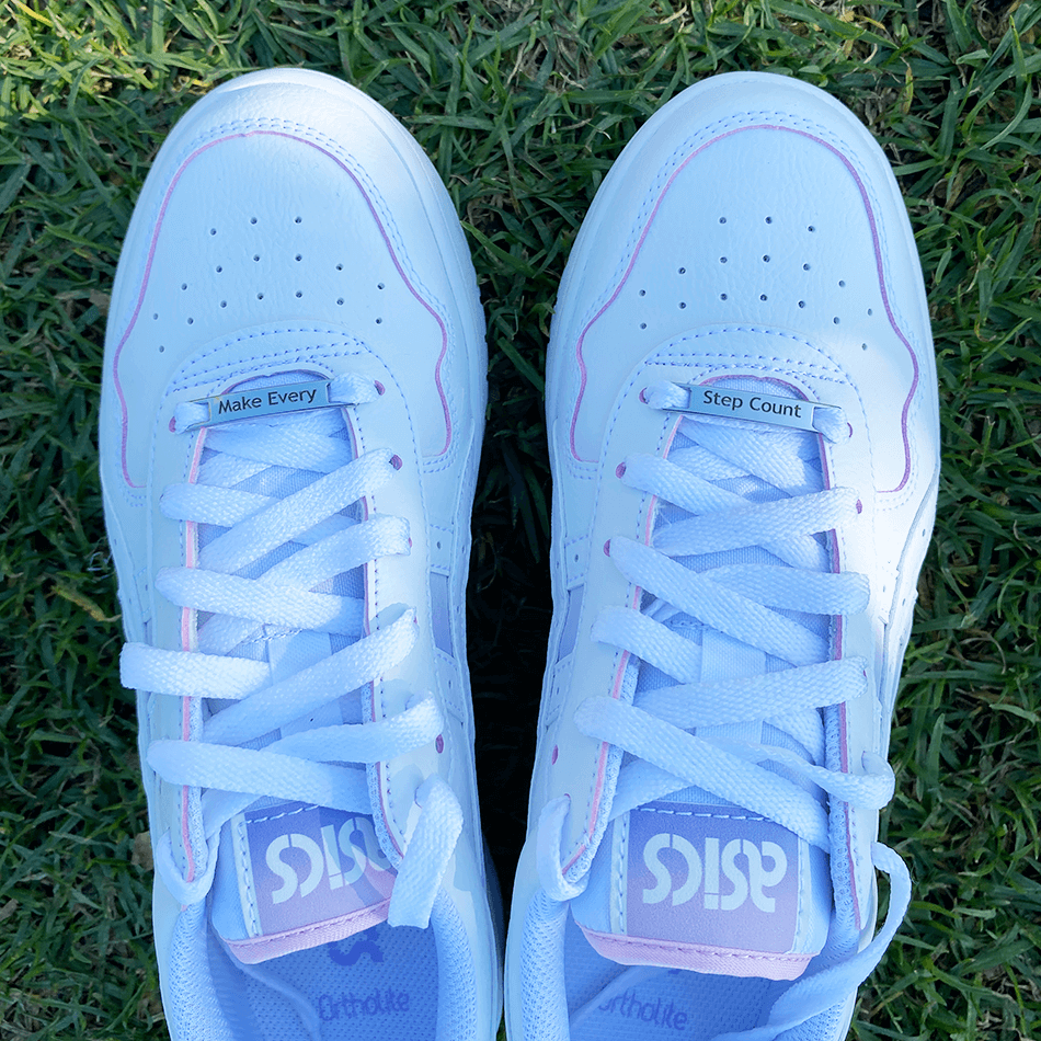 Image of etched shoe tags Make Every Step Count on a pair of shoes on grass