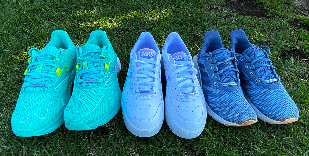 A row of shoes lined up horizontally on grass with different etched tags laced 