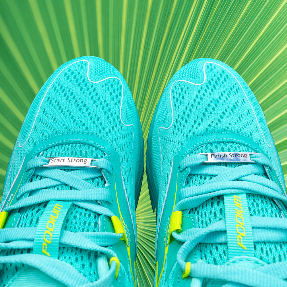 Image of etched shoe tags Start Strong Finish Strong on a pair of running shoes on a green textured background